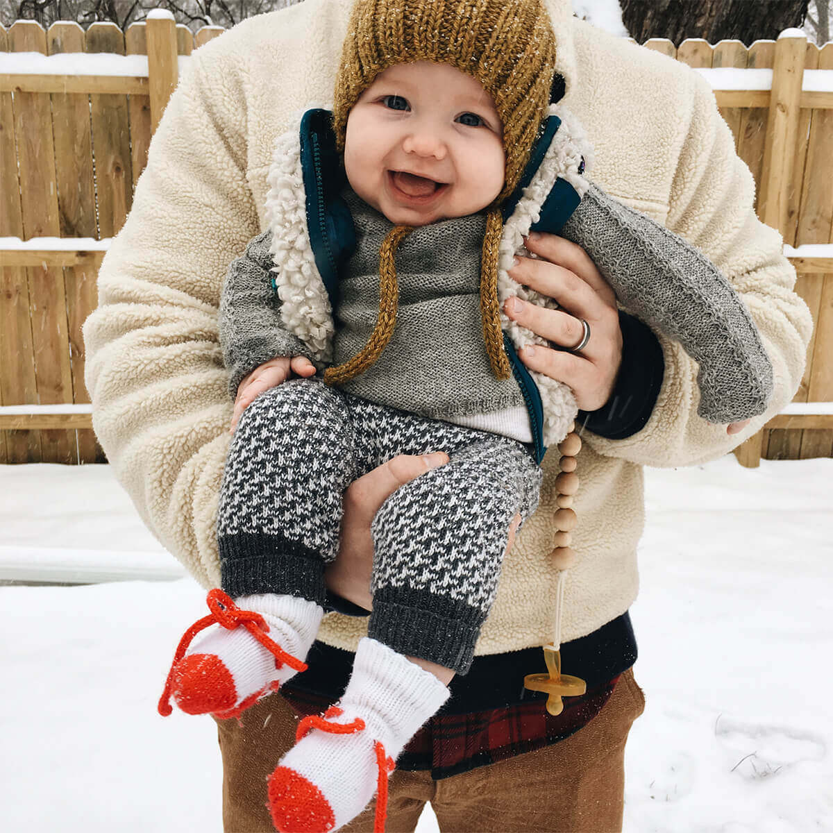 Baby in beanie outside laughing in dad's arms