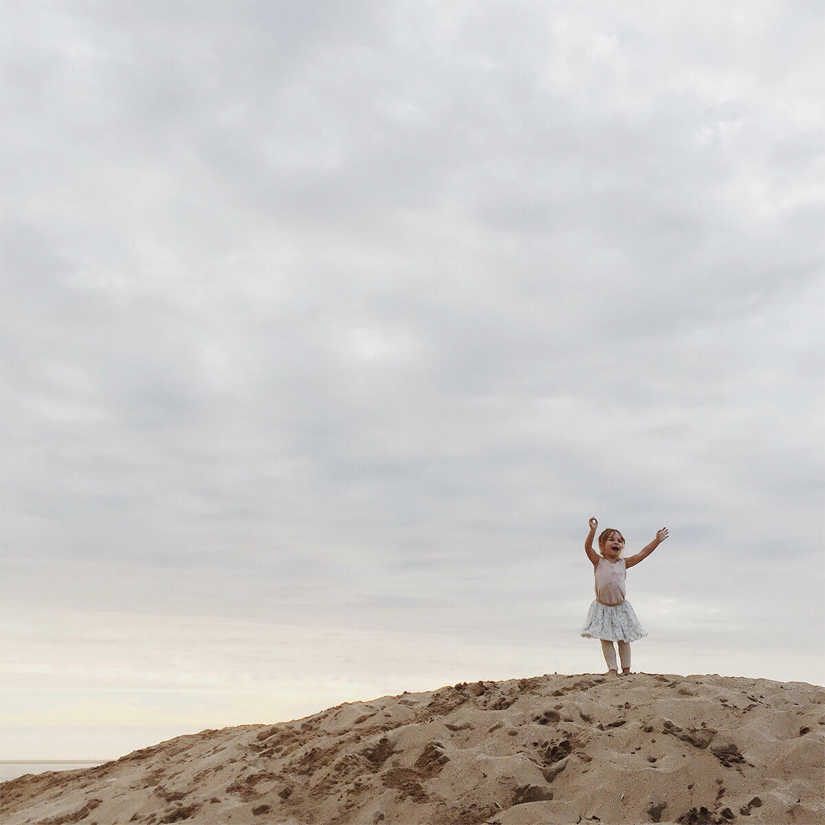 Little girl striking ballerina pose on top of a hill
