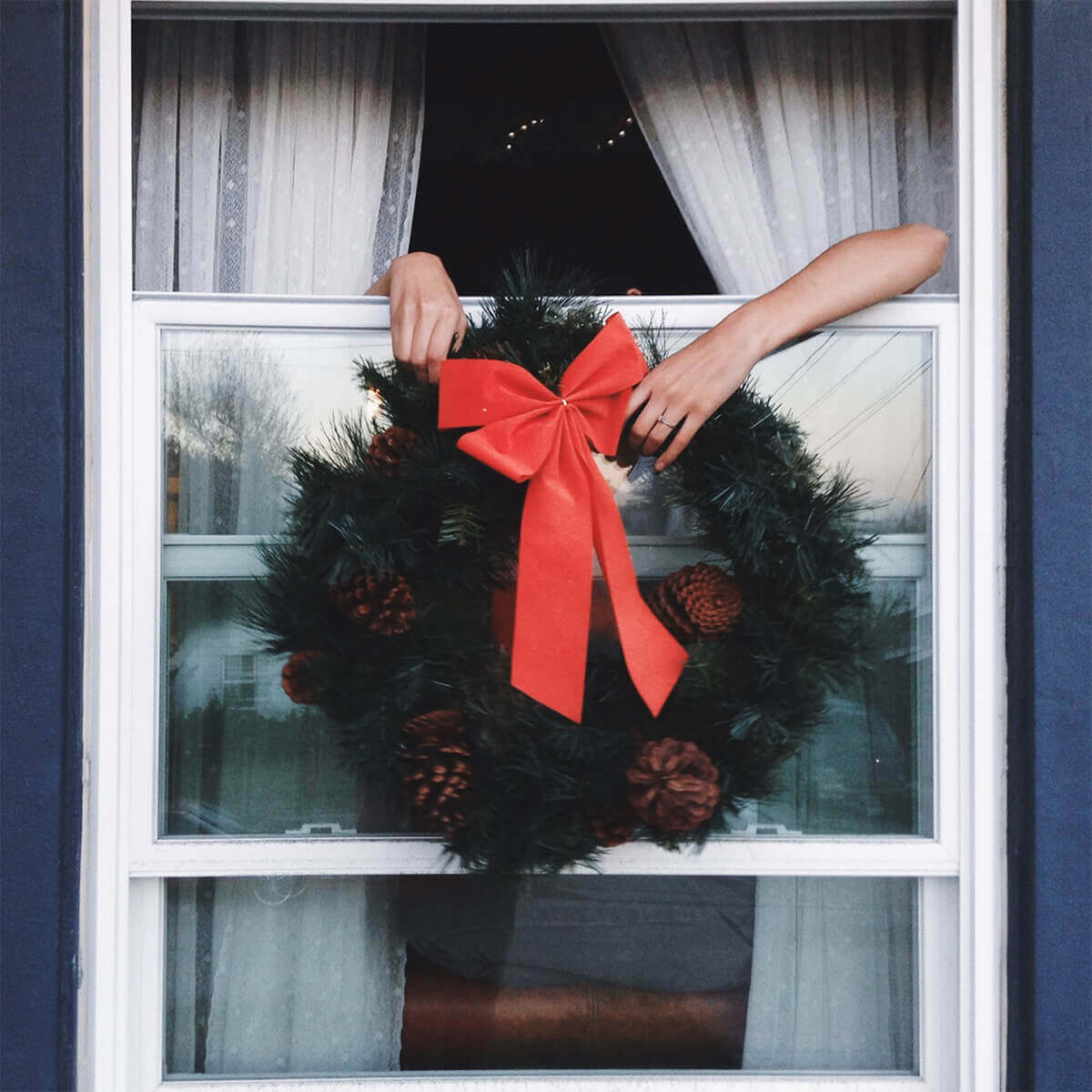 Hands holding a wreath out the window
