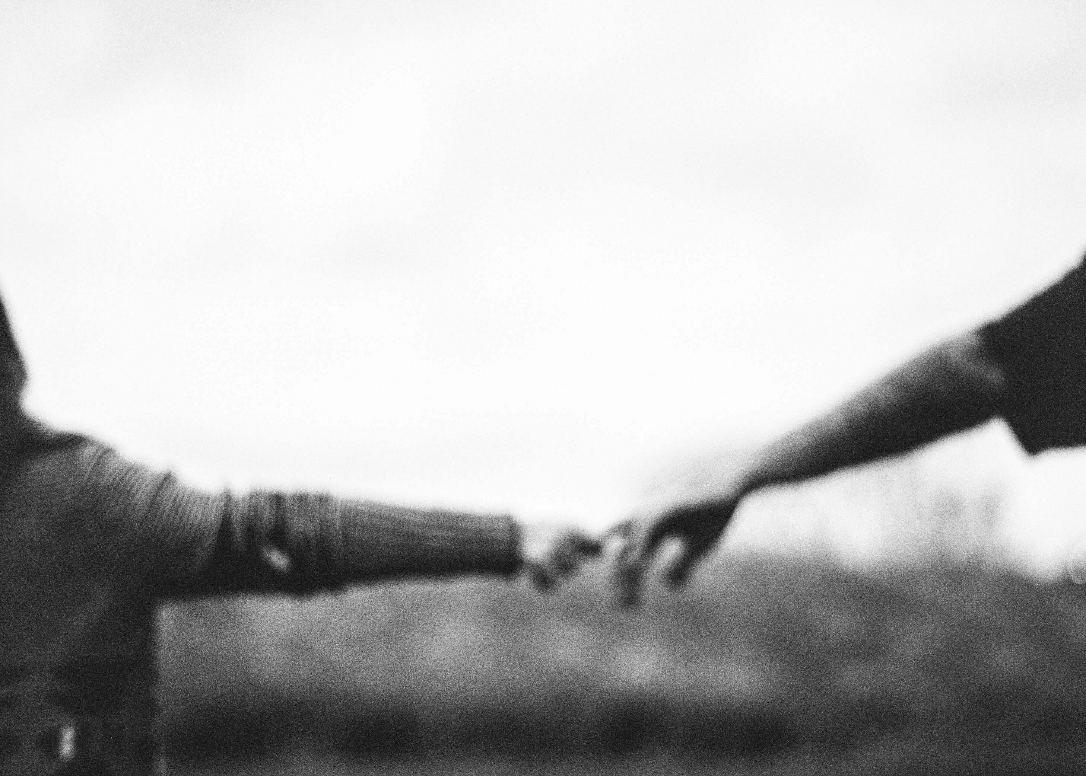 Black and white blurred photo of mother and little girl holding hands as they walk away from the camera