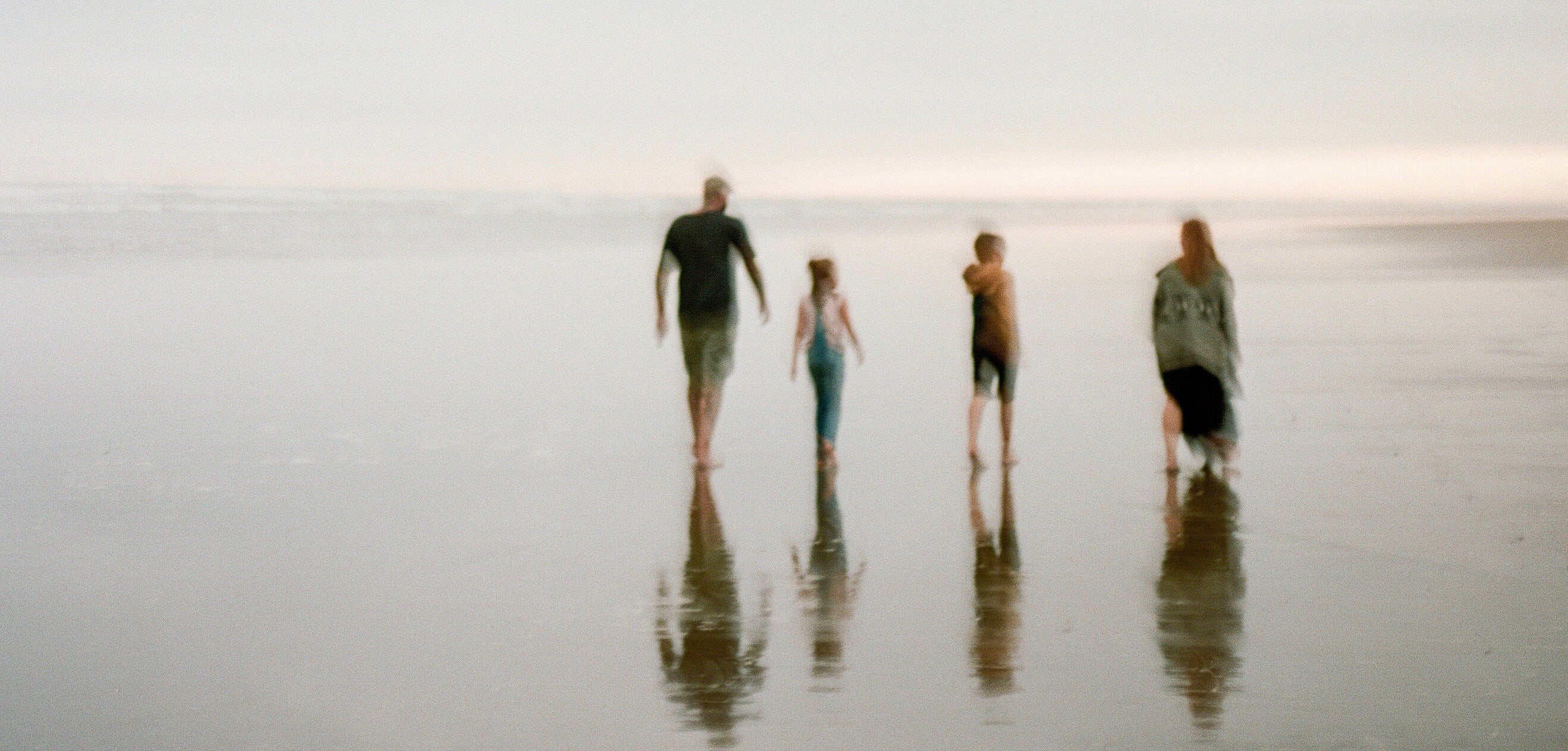 Blurred photo by Yan Palmer of family of four walking on beach