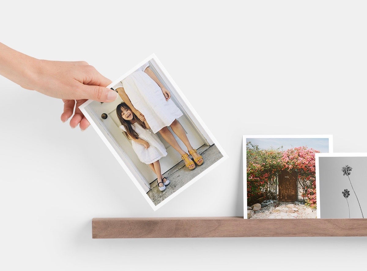 Hand placing photo print of little girl on Artifact Uprising Wooden Photo Ledge