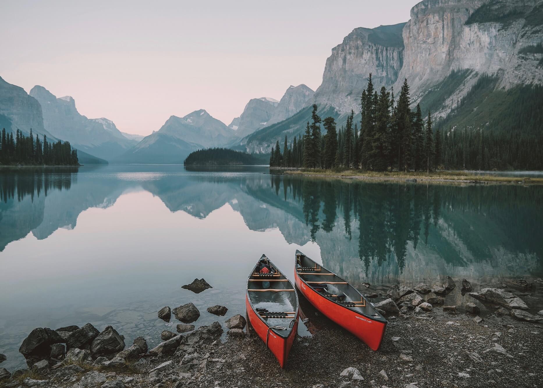 Emilie Ristevski photo of two empty canoes on the shore of an alpine lake