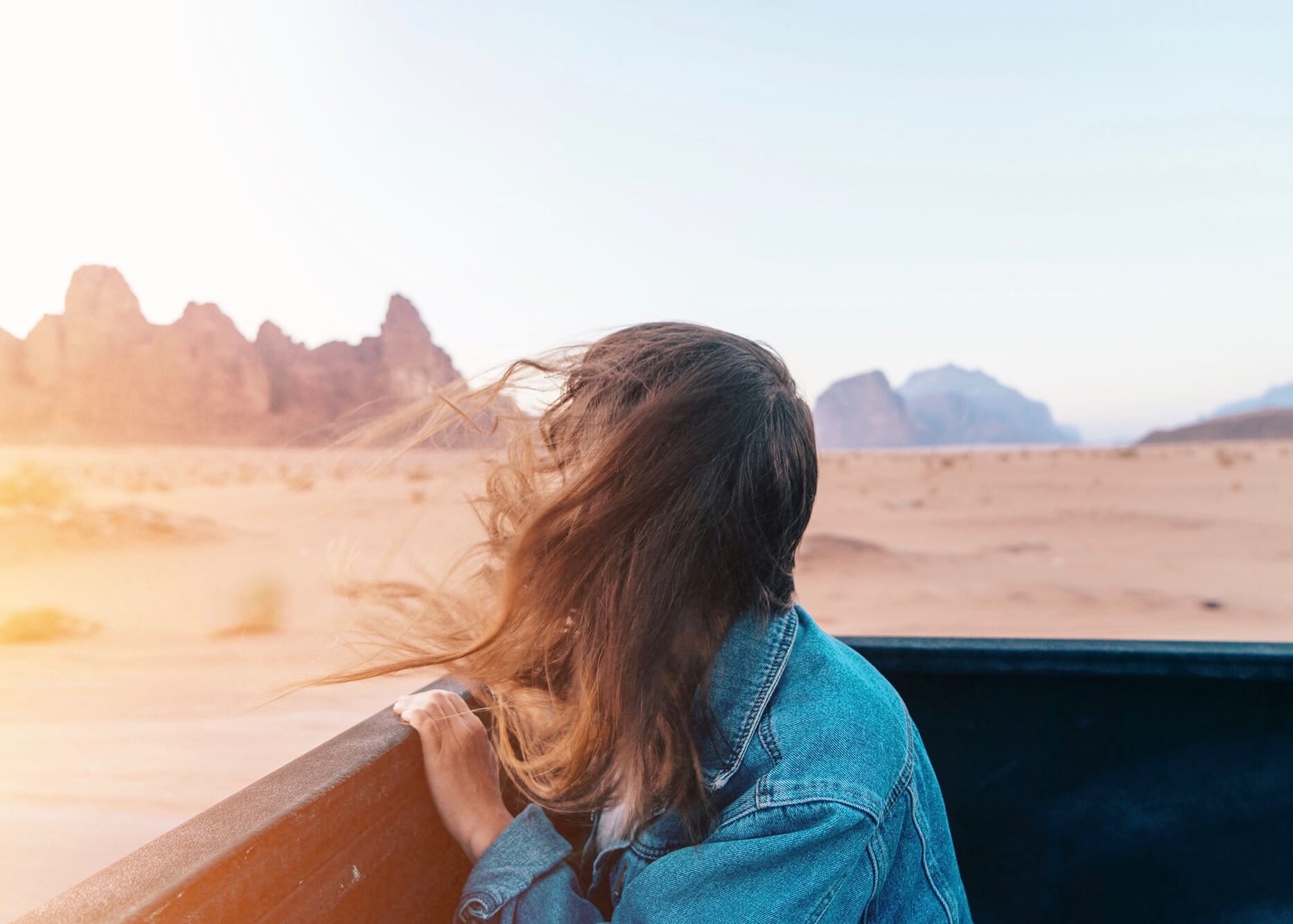 Woman in back of truck looking back across the desert