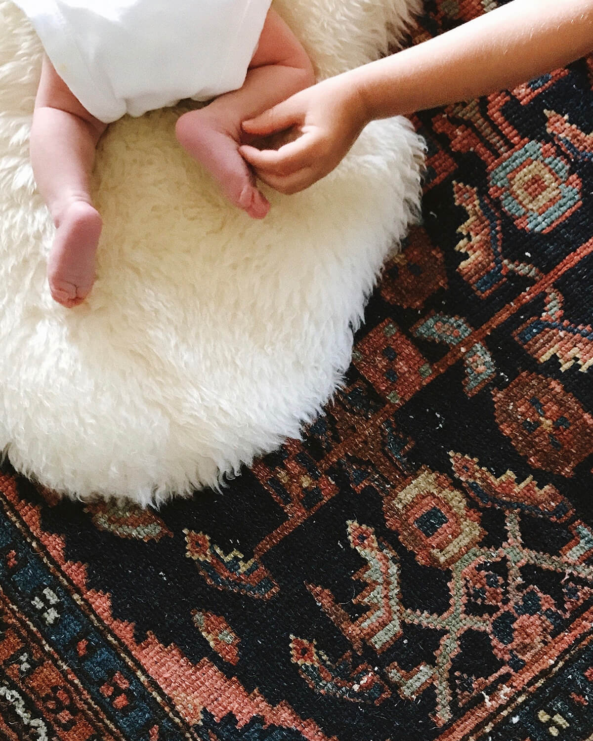 Hand tickling baby's foot with rest of the baby outside of the frame of the photo