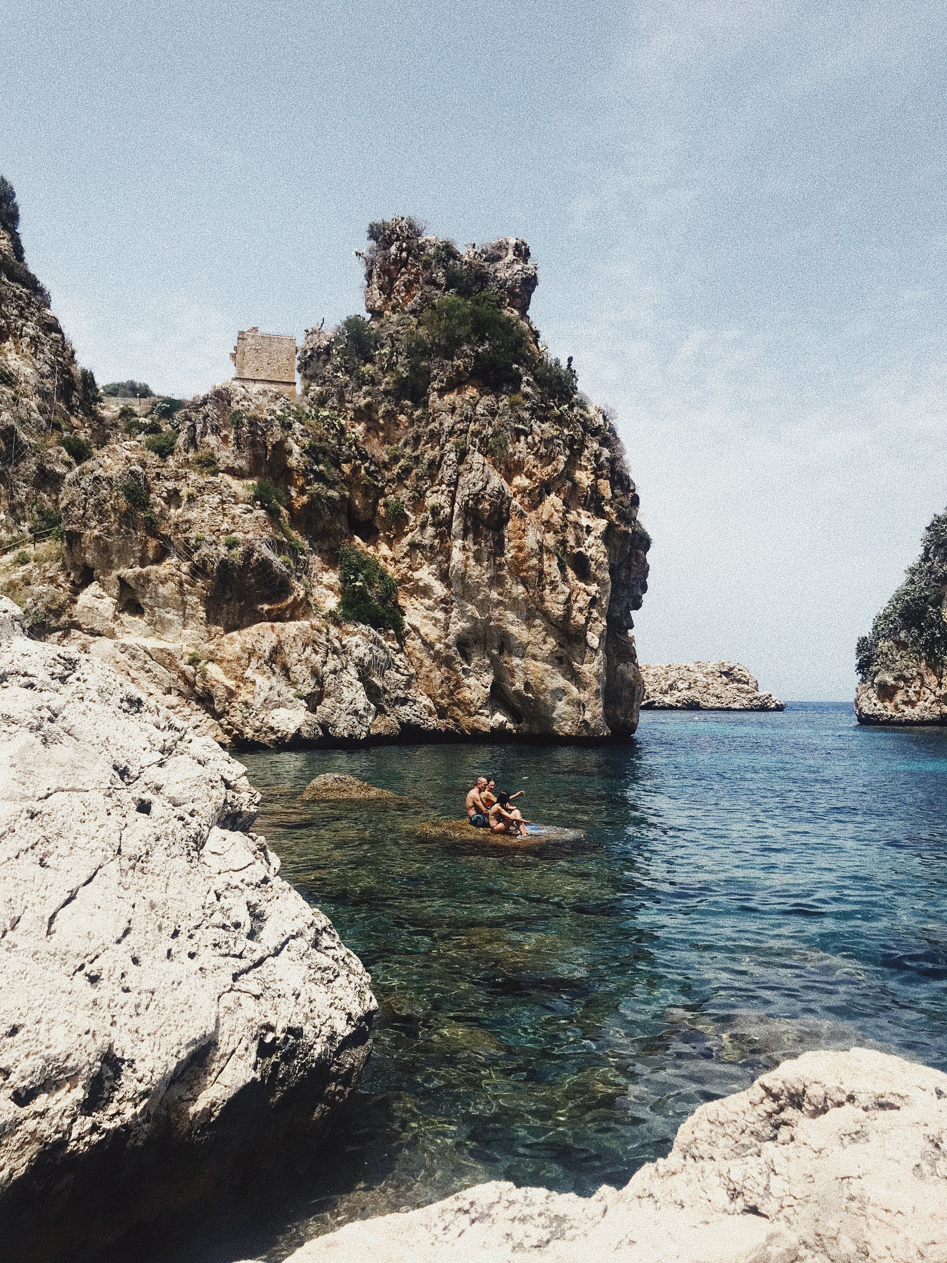 Lucy Laucht photo of three young people sitting on rock in the water