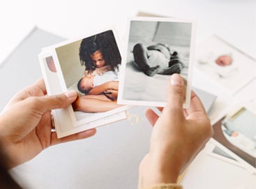 Woman's hands holding photos as she chooses which to put in her baby book