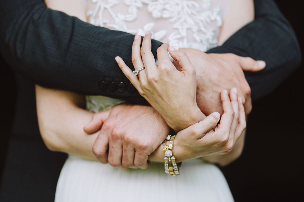 Close up image of bride and groom's hands around each other