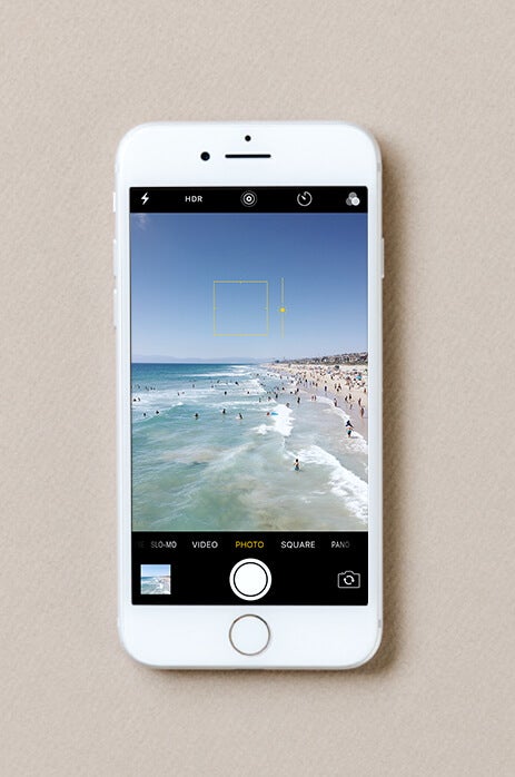 Photo of exposure being adjusted on iPhone taking photo of busy beach