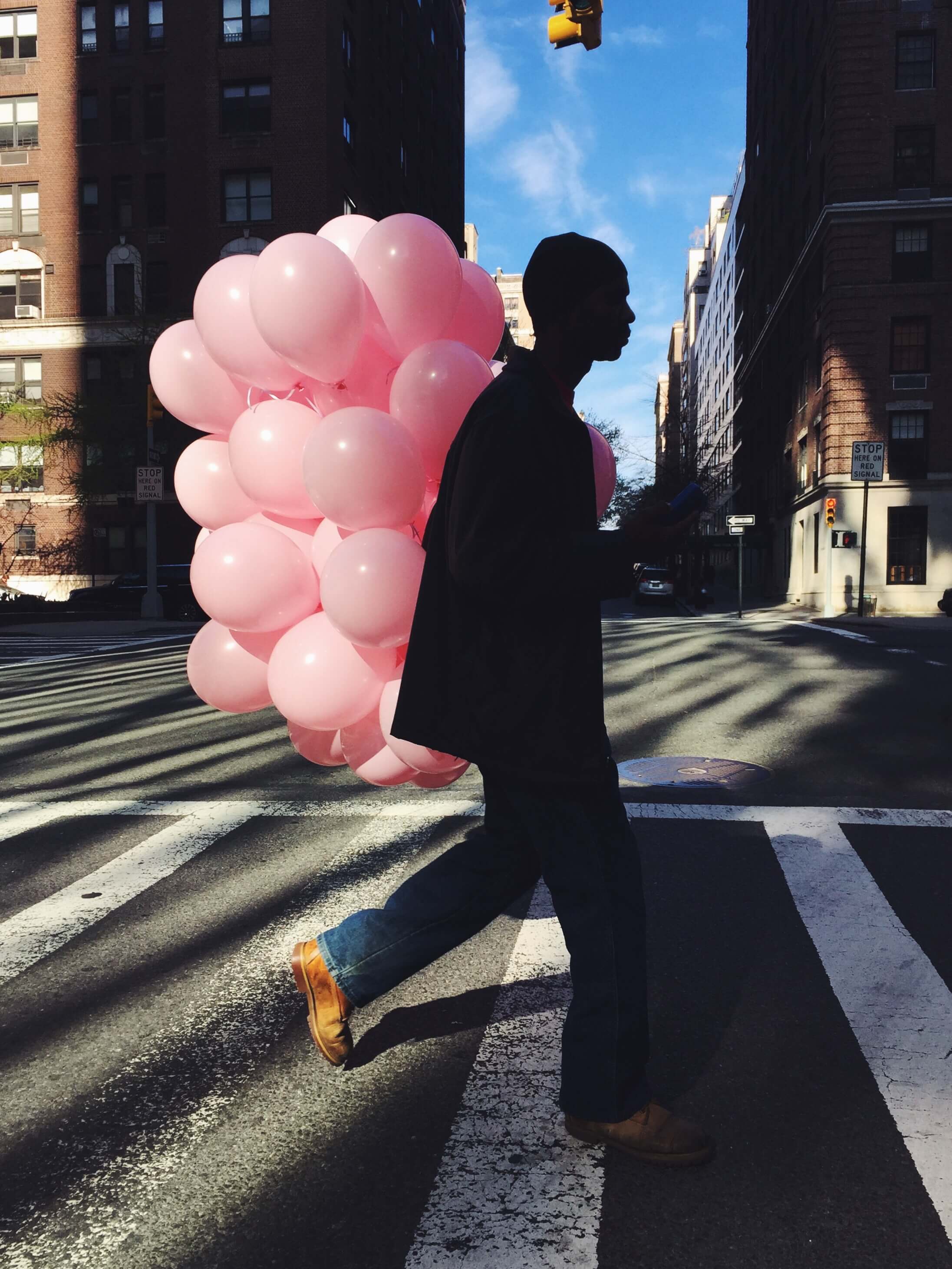 silhouette of a man carrying many pink balloons