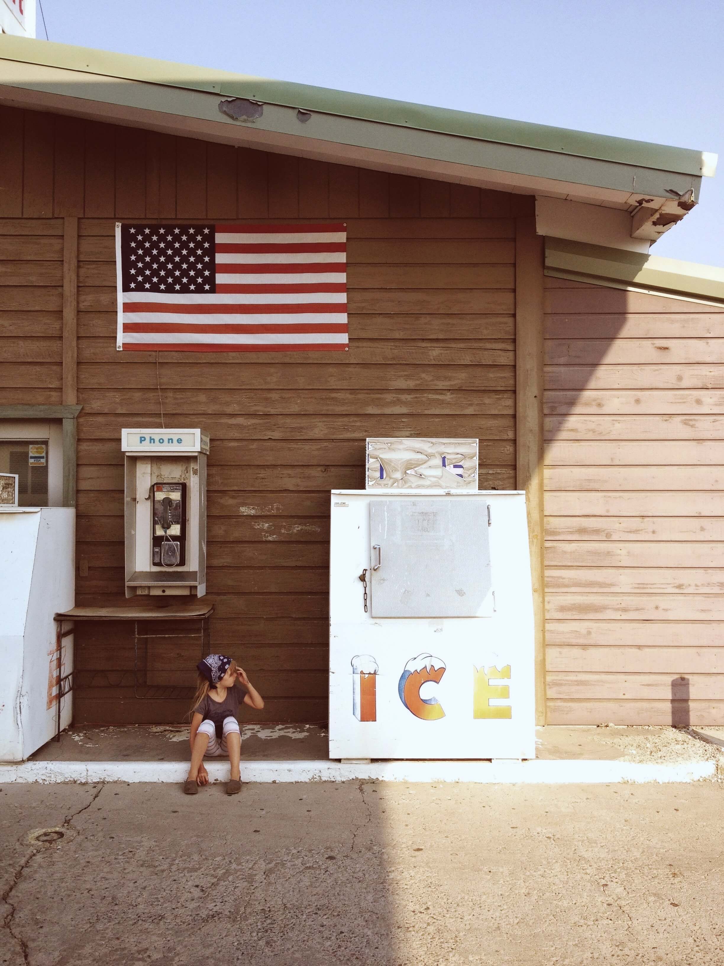 photo of child sitting outside of convenience store