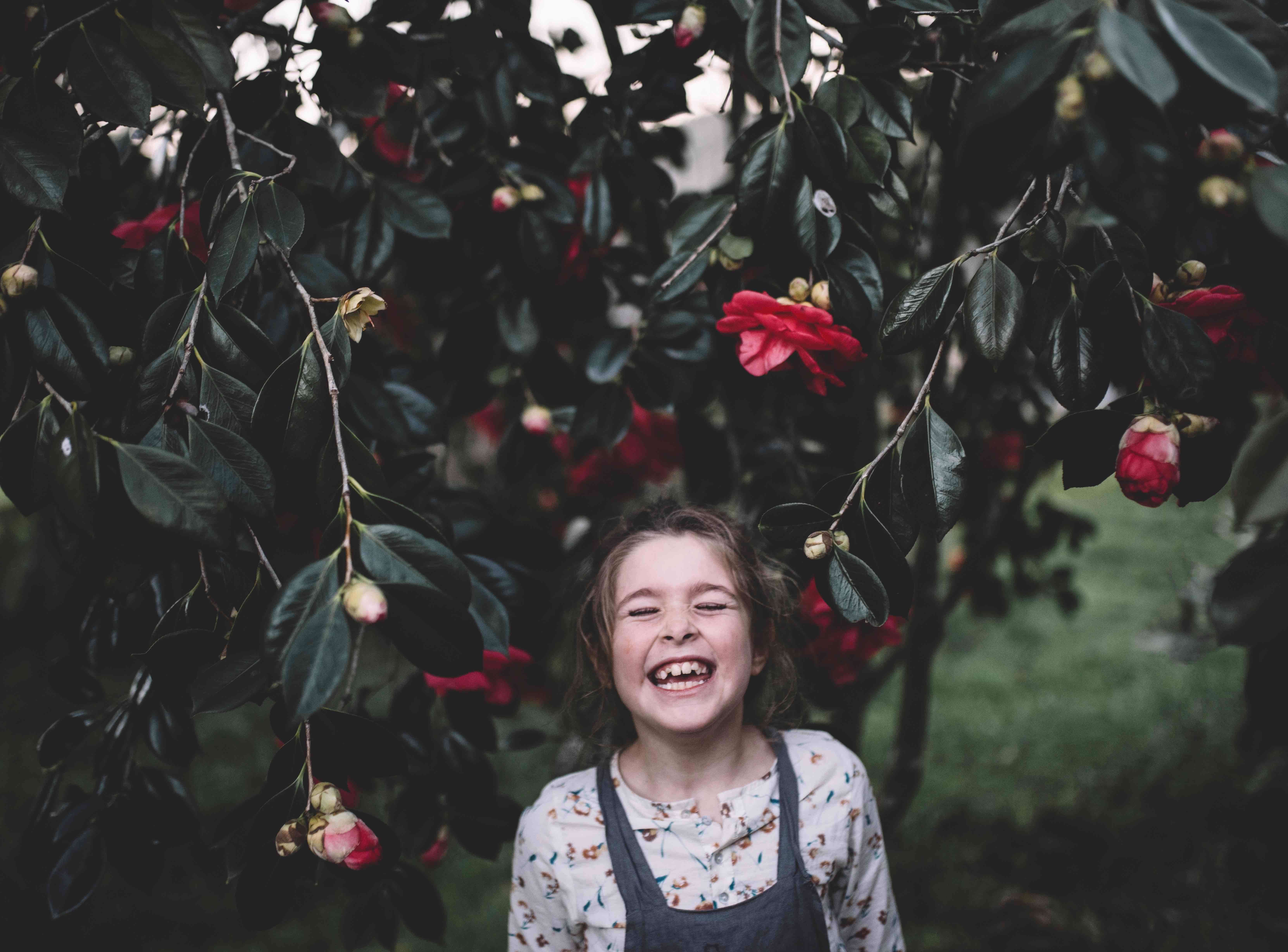 Young girl smiling with eyes closed under a flowering tree