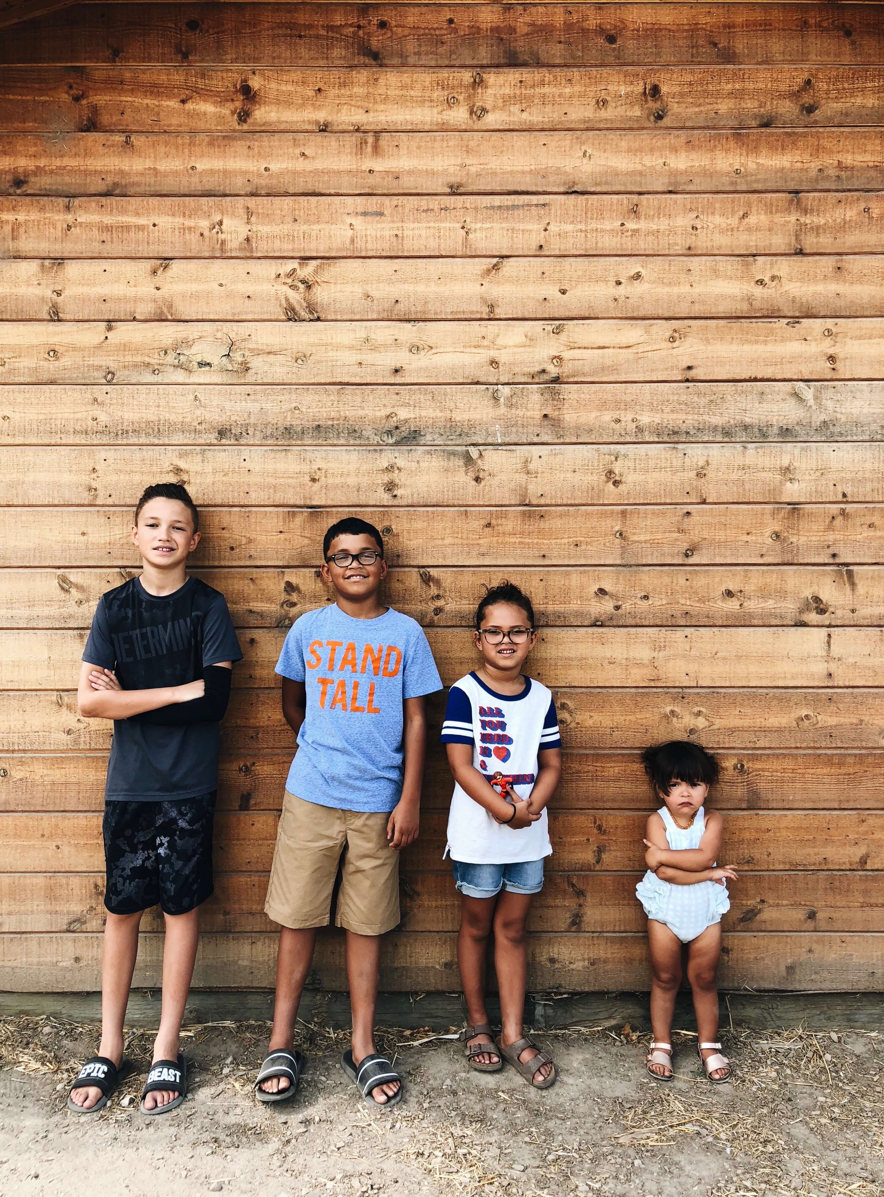 Four kids standing against wall in order of height