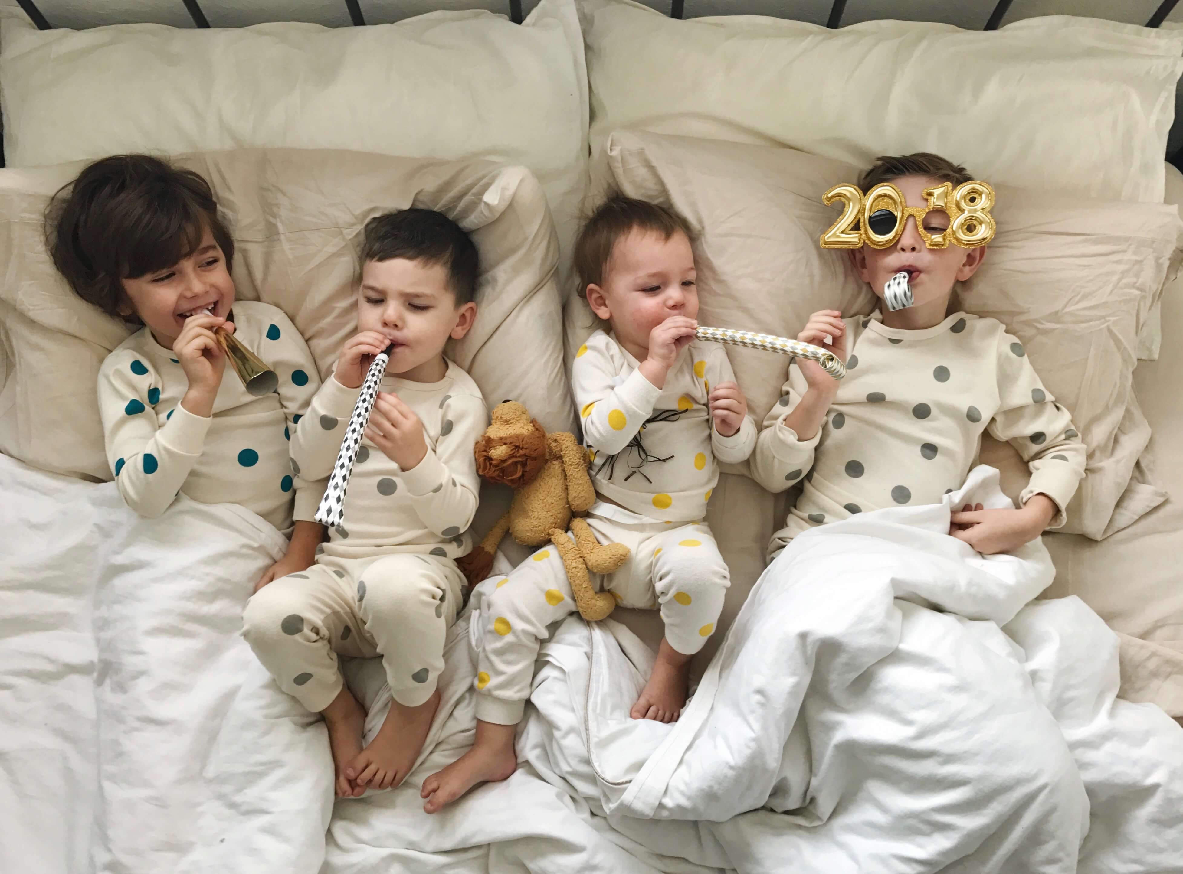 Four children lying in bed with new year's props