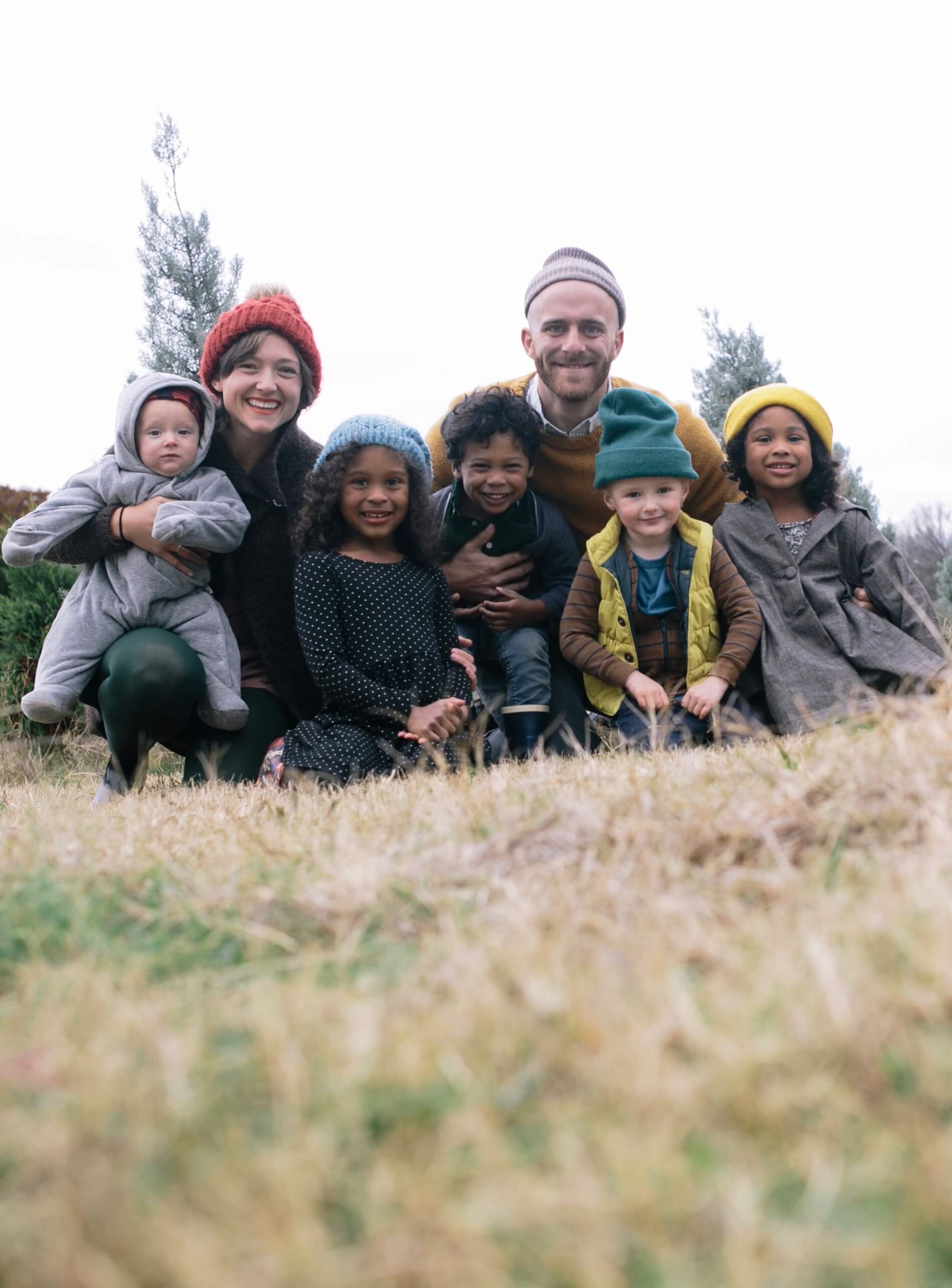 Family photo with parents and five young children all wearing beanies