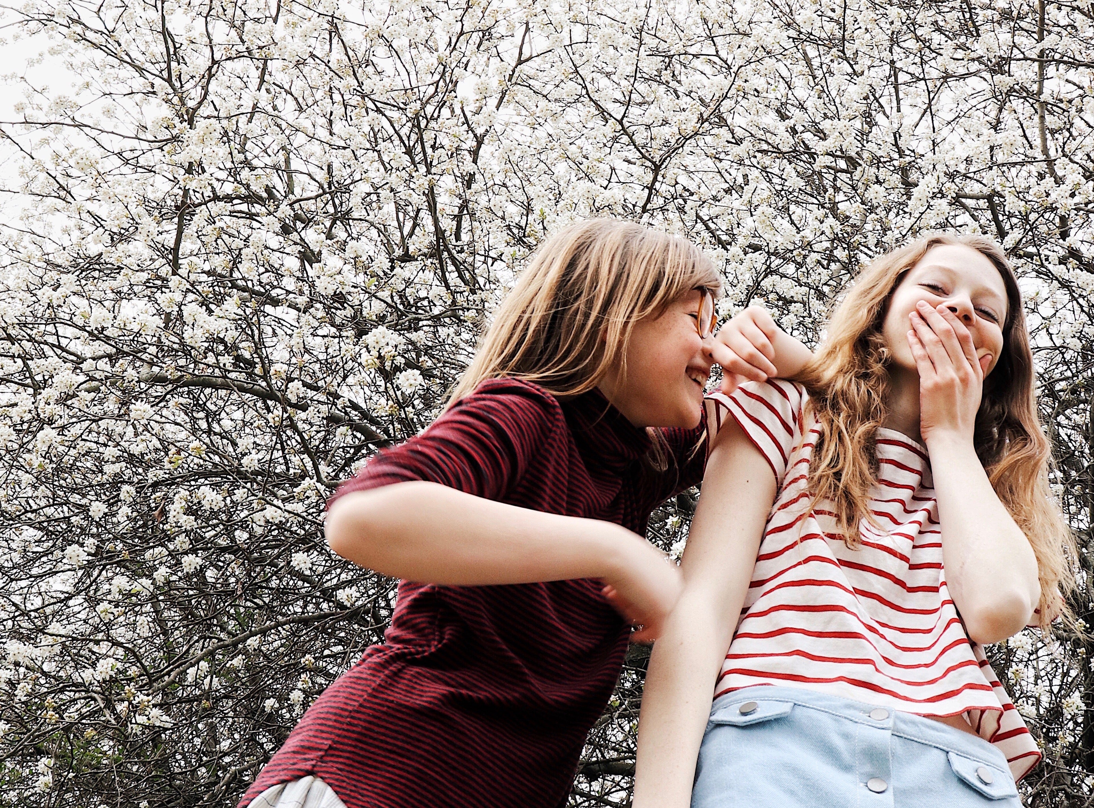 Two sisters laughing in front of flowering tree