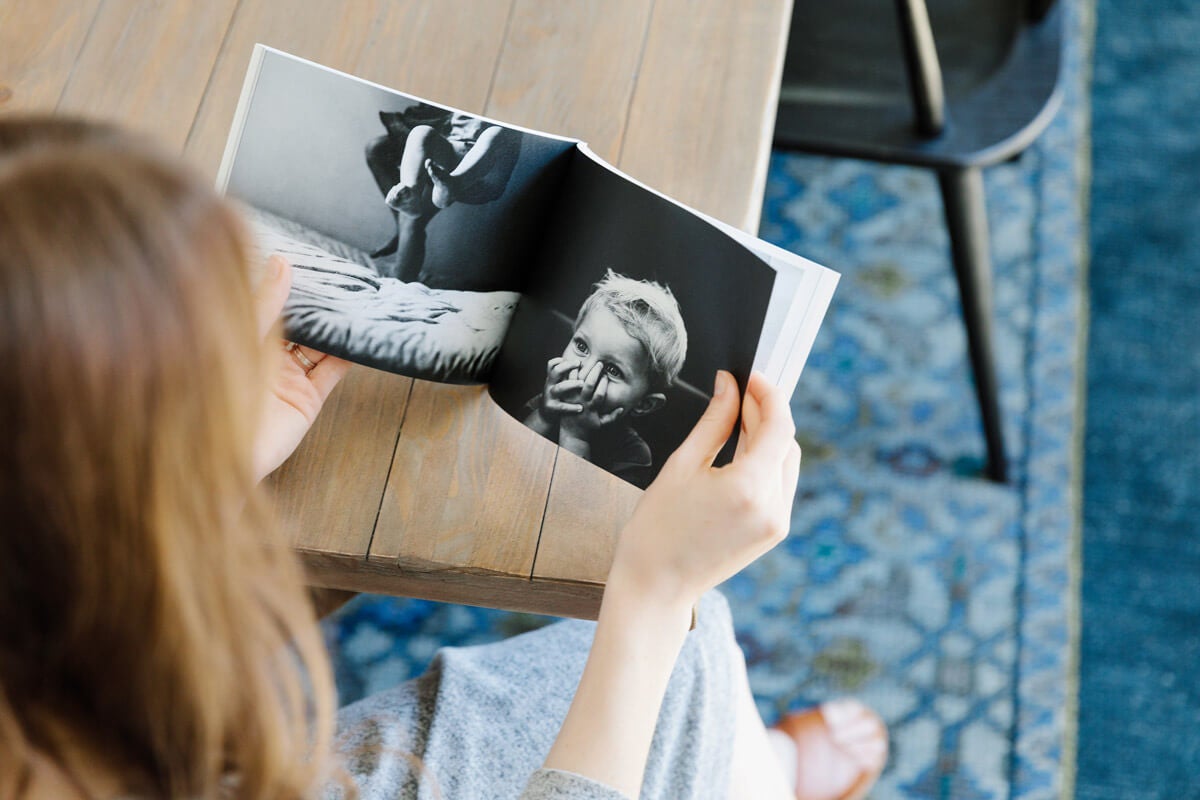 Woman flipping through softcover photo book at dining table